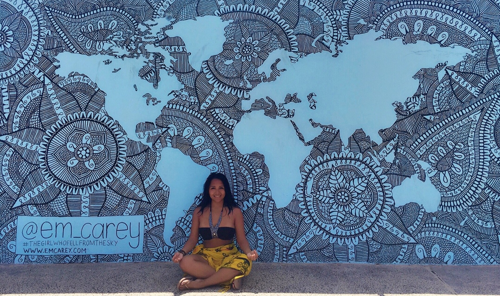 LuLu sitting below a world map mural